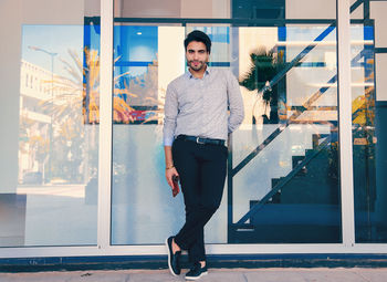 Full length portrait of young man standing against window