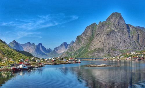 Village by sea and mountains against sky at lofoten