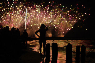 Silhouette woman watching firework display at night