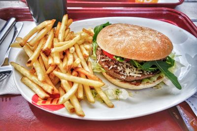 Close-up of burger and vegetables in plate on table