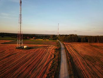 Road amidst field against sky during sunset