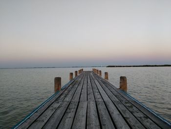 Pier over sea against sky during sunset