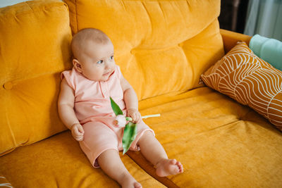 Child on a yellow sofa with flowers at home