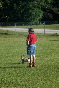 Full length of man with dog standing on grassy field