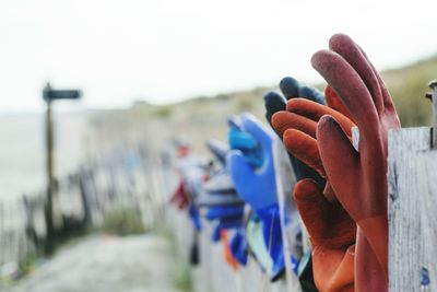 Gloves on fence against clear sky