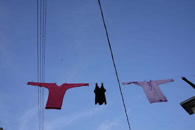 Low angle view of clothes drying on power lines against sky