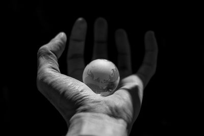 Close-up of hand holding lemon over black background