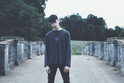 Portrait of young man standing against trees