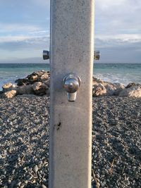 Close-up of metal container on beach against sky