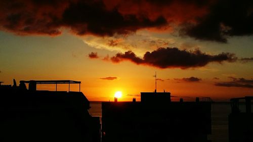 Silhouette buildings against sky during sunset