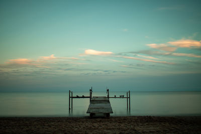 Pier over sea against sky during sunset