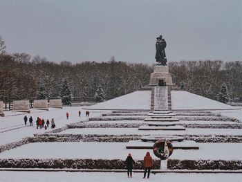 People on snow covered landscape against clear sky