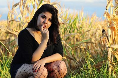 Young woman crouching on grassy field