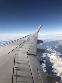 Airplane flying over clouds against blue sky