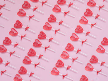 Red heart lollipop pattern on pink background