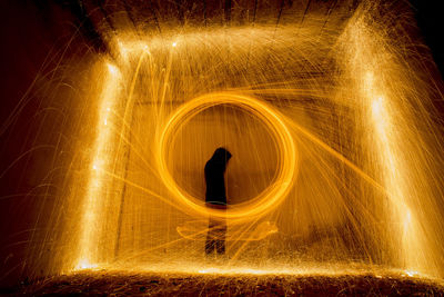 Silhouette person spinning wire wool at night