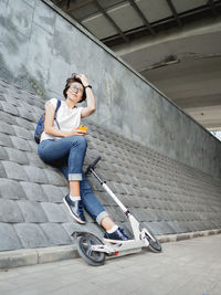 Smiling woman texting on smartphone after riding eco-friendly kick scooter. 