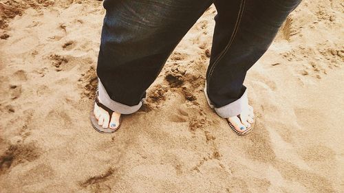 Low section of woman standing on sand