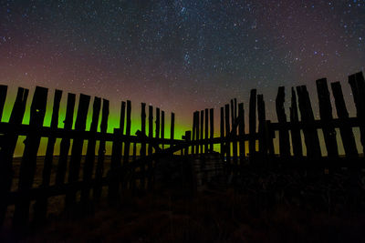 Northern lights behind an old fence