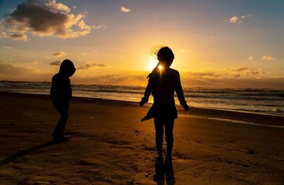 Silhouette woman standing on beach against sky during sunset