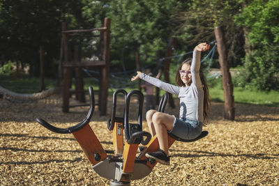 Caucasian beautiful girl spinning swing in the park at the playground