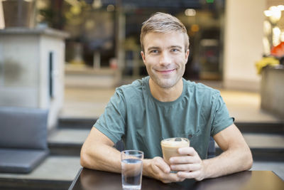 Portrait of smiling young man having coffee in restaurant