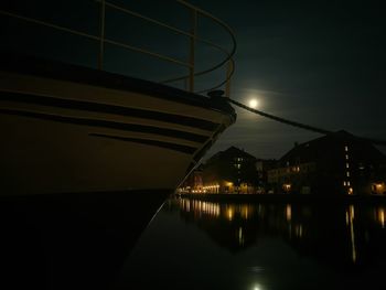 Illuminated city by river against sky at night