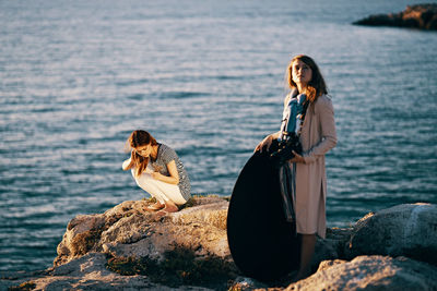 Woman sitting on rock by sea