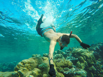 Full length of shirtless young man swimming undersea