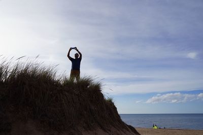 Man photographing while standing at sea against sky