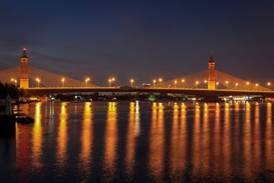 Illuminated bridge over river at night