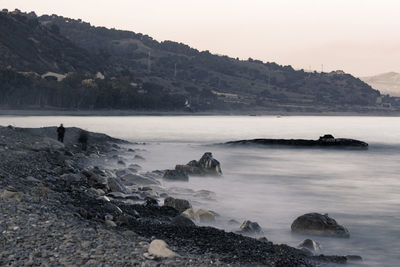 The sea wraps the rocks of the ionian coast in italy in a late winter afternoon