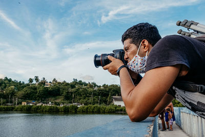 Side view of couple holding hands against lake