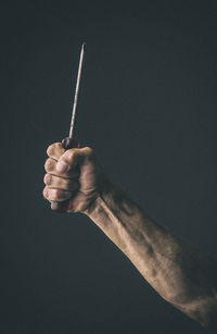 Close-up of person holding screwdriver against black background