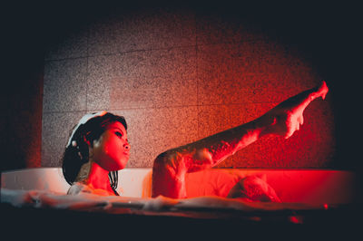 Side view of young woman bathing in bathtub at home