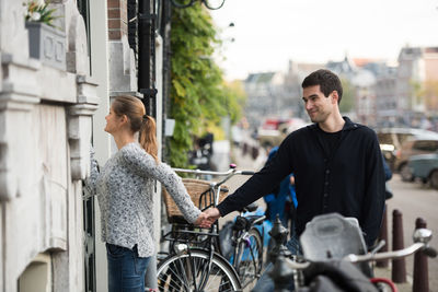 Young couple holding hands by building in city