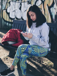 Young woman using phone while sitting on seat