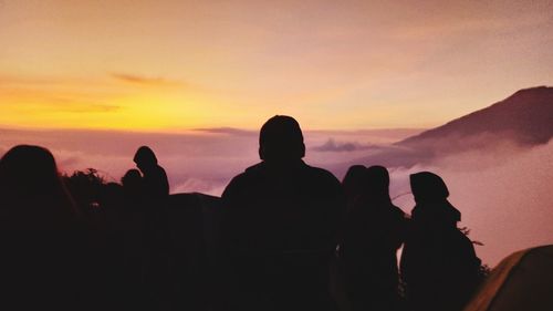 Silhouette people against orange sky