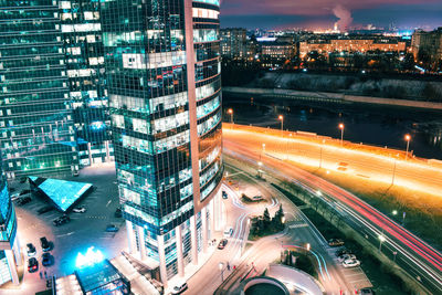 High angle view of light trails on city street by buildings