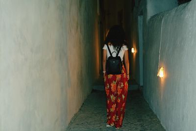 Rear view of woman standing against wall