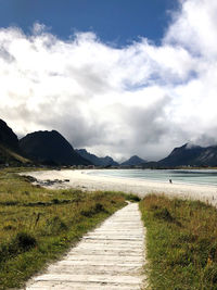 Road leading towards mountains against sky