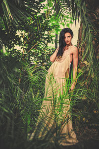 Portrait of smiling young woman standing on grass against trees