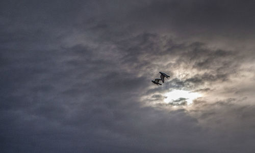 Low angle view of silhouette airplane flying against sky