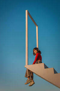 Low angle view of woman standing against blue sky