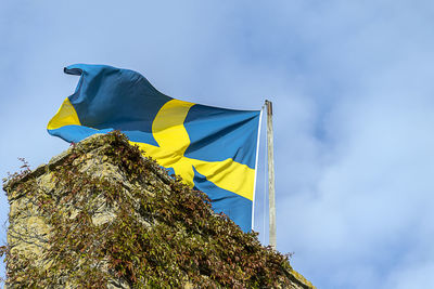 Low angle view of flag against blue sky