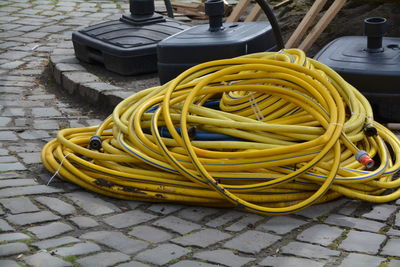 High angle view of yellow hose on paving footpath in yard