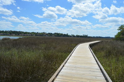 Boardwalk on field against sky