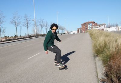 Young man skateboarding on road in city
