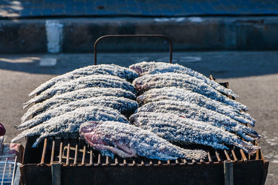 High angle view of fish covered with salt on barbecue at market stall