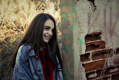 Happy teenage girls standing by broken wall